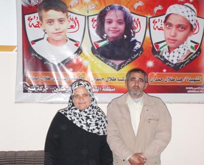 Iman and Talal Hamdan standing in front of a picture of their killed children Hiya, Lama and Ismail.