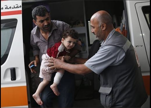 A Palestinian carries a wounded child to the emergency room at Shifa Hospital. 20 July. Credit: Lefteris Pitarakis/AP