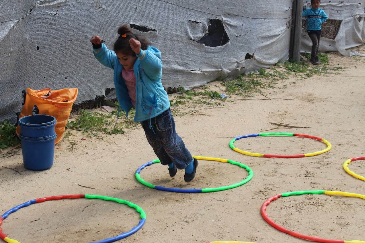 Young girl in Gaza jumps from hoop to hoop during psychosocial activity