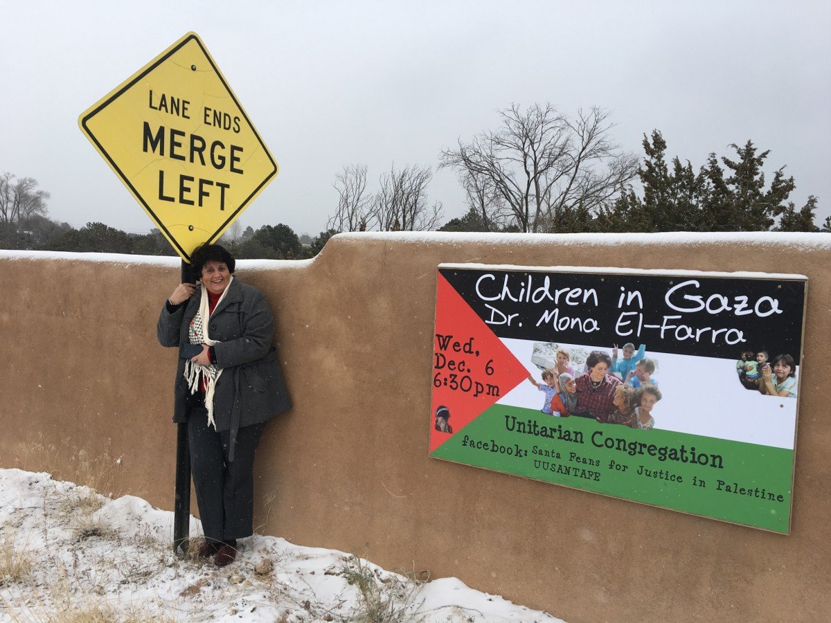 Dr Mona El-Farra standing next to a Palestinian flag in Santa Fe, New Mexico