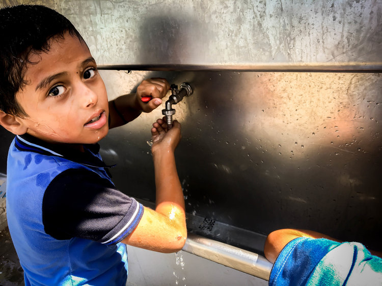 Boy drinking clean water at school in Gaza