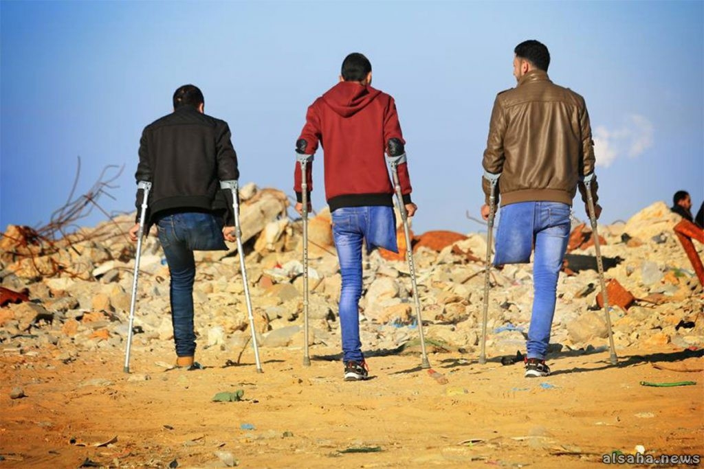 3 youth in Gaza on crutches in front of rubble